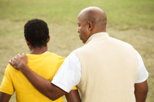 father talking to son while giving embrace