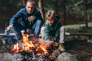 O pai e o filho assam os marshmallows no fogo do acampamento