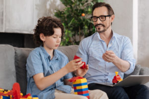 serious boy assembling erector set with his father on couch