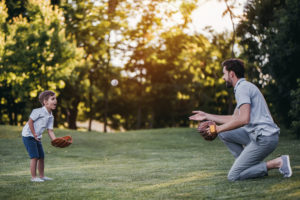 dad and son playing catch in a field