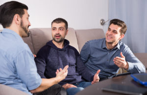 male friends enjoying сonversation on sofa at home