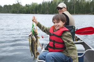 Vader en zoon op boot zoon houdt trots vangst omhoog