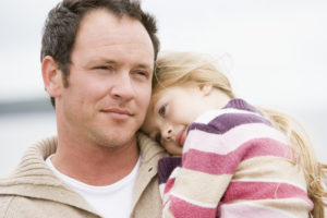 Father hold daughter resting on his shoulder